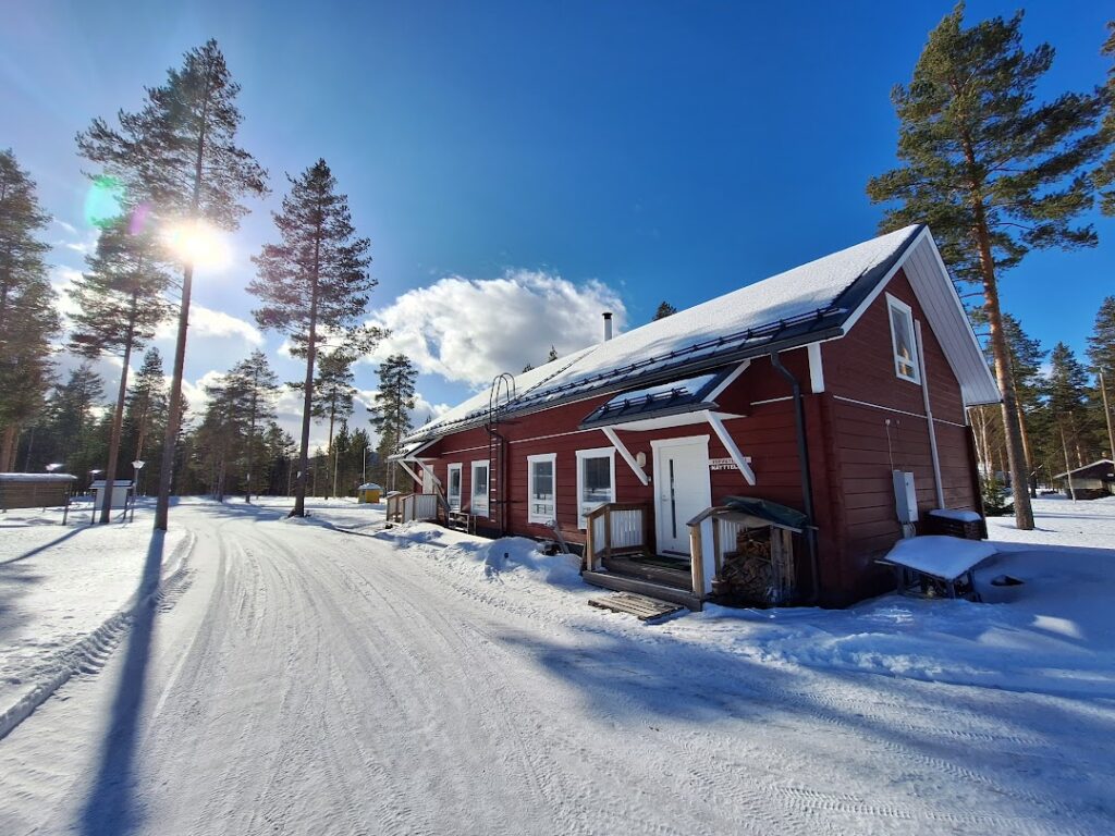 Red wooden building in the white snow winter setting, with sunny bright blue sky