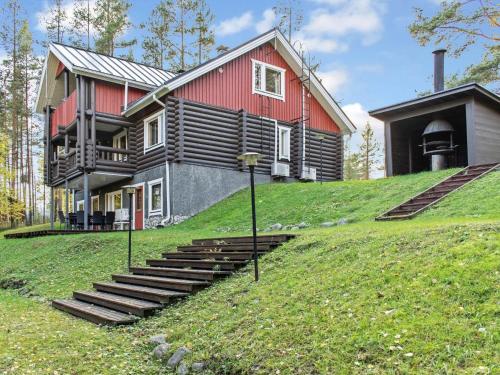 Three story red & black log villa with green crass and strairs.